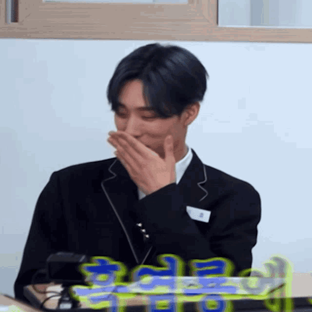 a man in a suit is covering his mouth with his hands