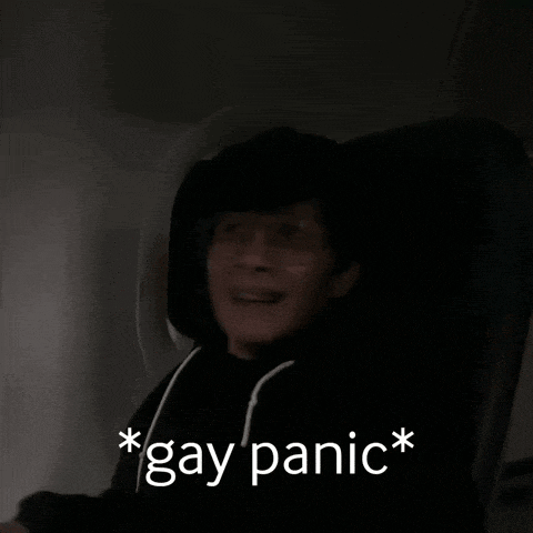 a man in a black hoodie is sitting in a dark room with the words gay panic above him