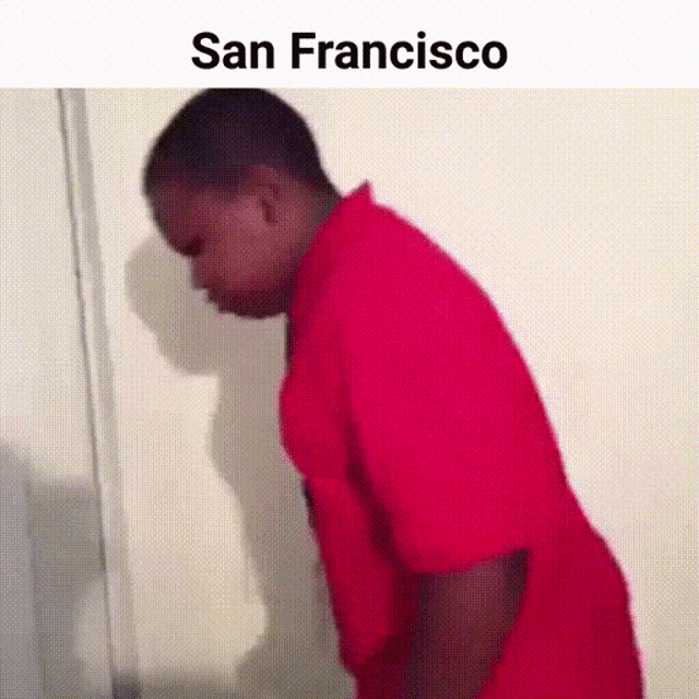 a man in a red shirt is leaning against a wall with the words san francisco written above him