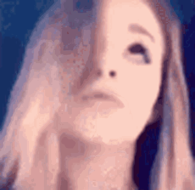 a close up of a woman 's face with her eyes closed and her hair blowing in the wind .