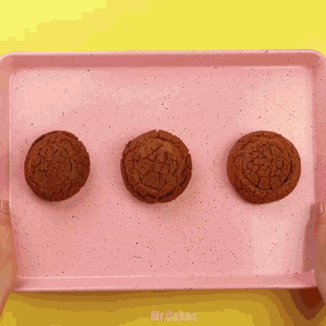 three chocolate cookies on a pink tray with mr. cakes written on the bottom