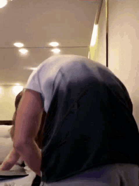 a man in a black shirt is bending over and looking at something on a table .