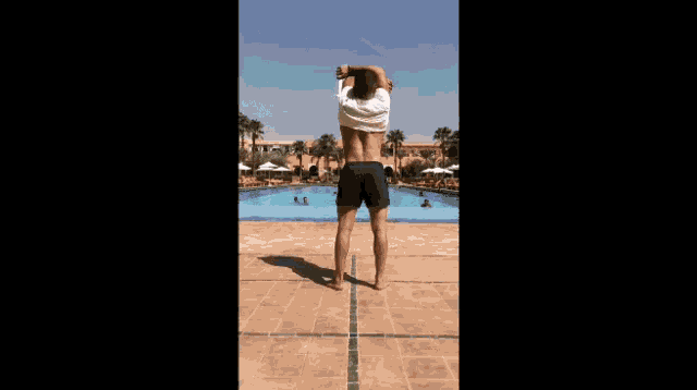 a man is standing in front of a swimming pool with his shirt off .
