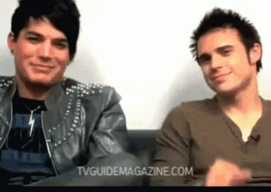 two men are sitting next to each other and the website tvguidemagazine.com is visible