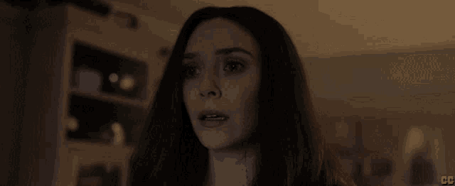 a woman with long red hair is standing in a dark room looking at the camera .