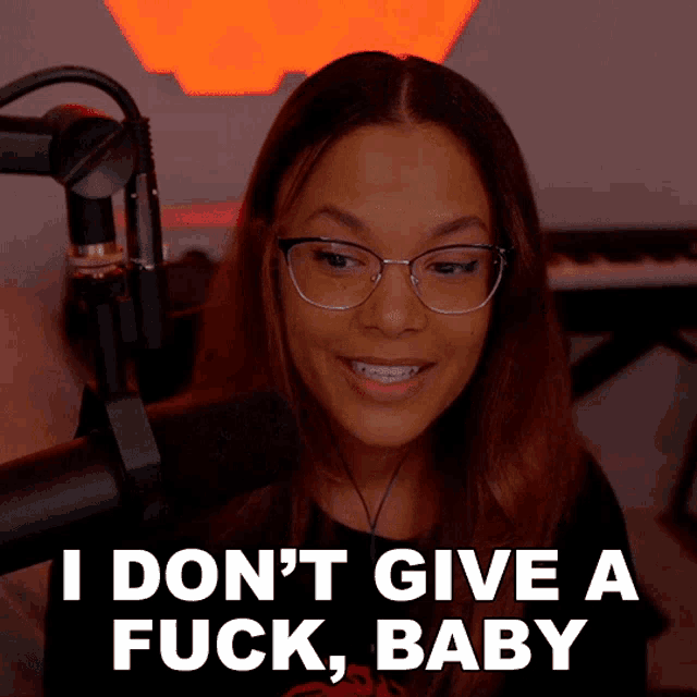a woman in front of a microphone with the words " i don 't give a fuck baby " below her