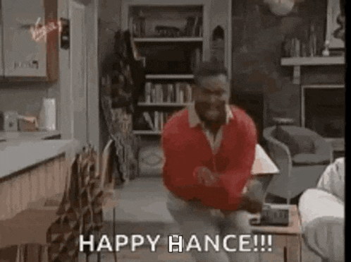 a man in a red sweater is kneeling down in a living room and dancing .