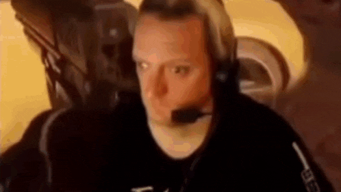 a man wearing headphones and a headset is sitting in an airplane .