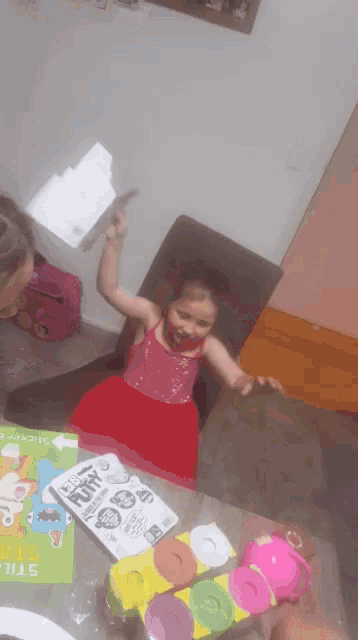 a little girl is sitting at a table holding a piece of paper that says " free " on it ..