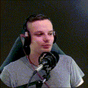 a man wearing headphones and a gray shirt is sitting in front of a microphone