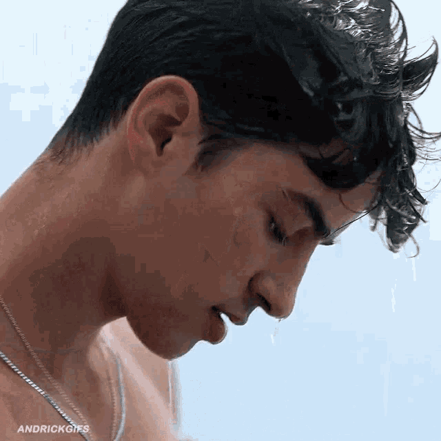 a close up of a man taking a shower with his eyes closed and water dripping from his nose .
