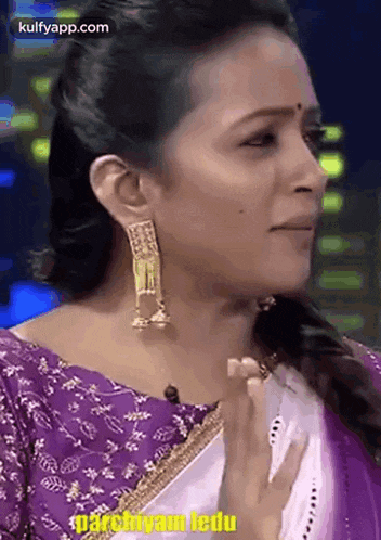 a close up of a woman wearing a purple blouse and white saree .