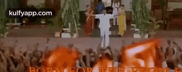 a man in a white shirt is standing in front of a crowd of people holding red flags .