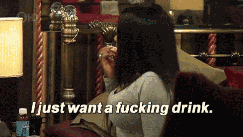 a woman sitting on a couch with the words i just want a fucking drink