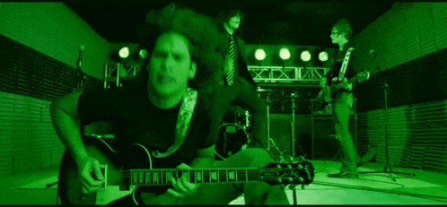 a man is playing a guitar in a band in a dark room