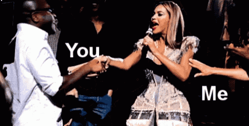 a woman is singing into a microphone while a man holds her hand and says " you me "