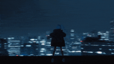 a silhouette of a person standing in front of a city skyline