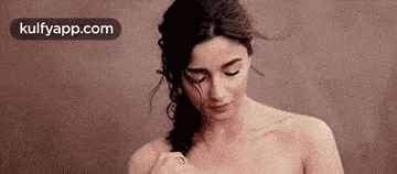 a naked woman is standing in front of a brown background .