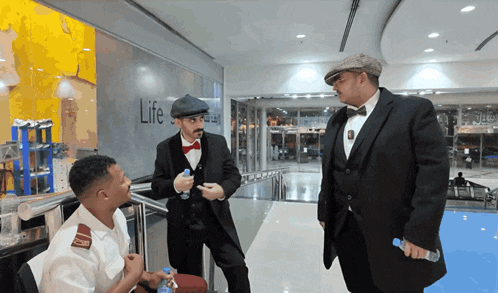 three men are standing in front of a wall that says life
