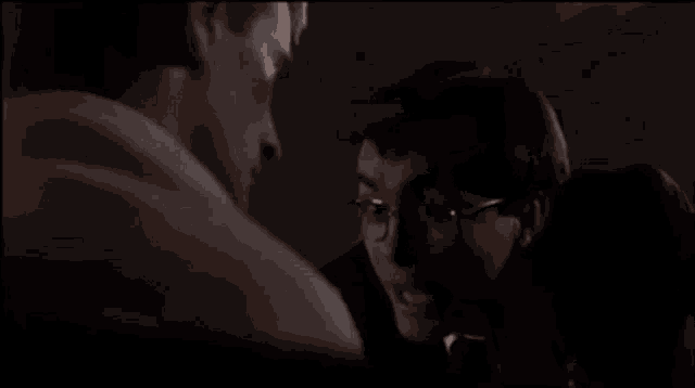 a man and woman are kissing in a dark room in a movie .