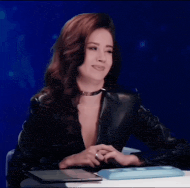 a woman in a black leather jacket sitting at a desk