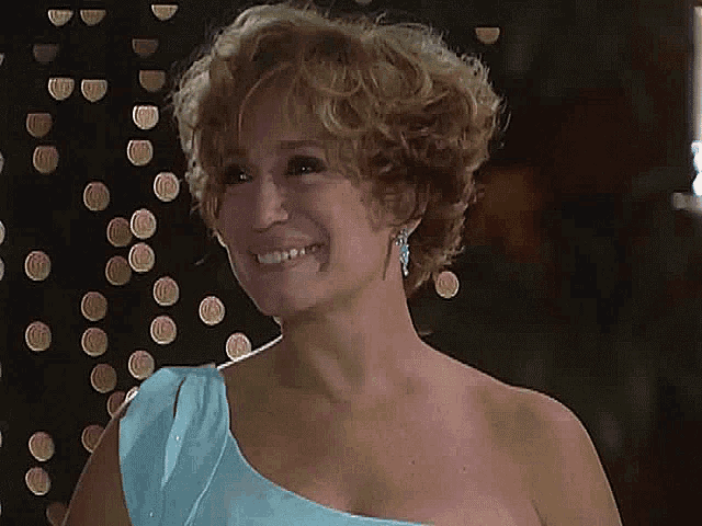 a woman wearing a blue one shoulder dress smiles