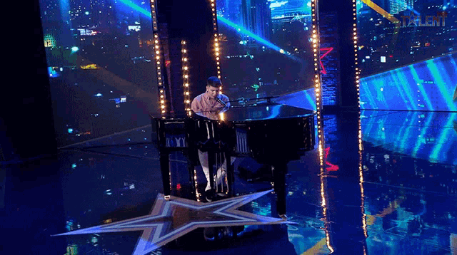 a man sings into a microphone while playing a piano on a stage