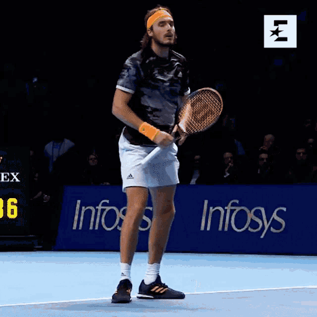 a man holding a tennis racquet on a tennis court in front of an infosys sign