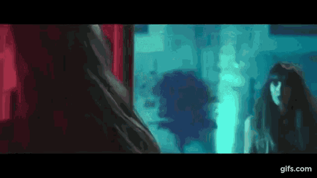 a woman is standing in front of a mirror and looking at herself .