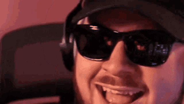 a man wearing sunglasses and headphones is smiling and making a funny face .