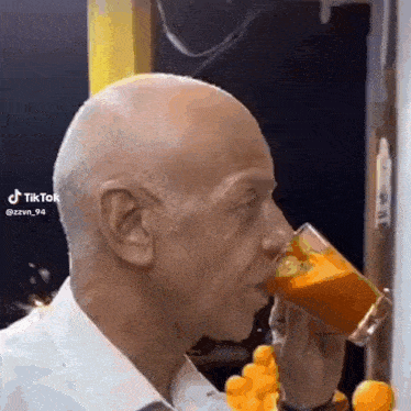 a man is drinking a glass of orange juice .