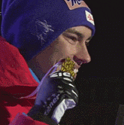 a man wearing a blue hat and a red jacket is holding a gold medal