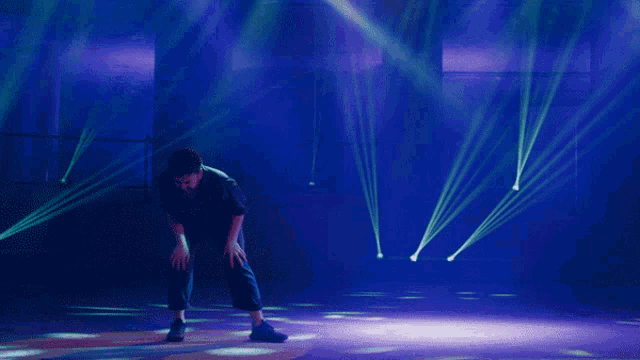 a man is kneeling down in front of a stage with blue lights