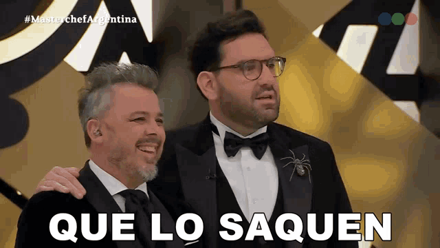 two men in tuxedos are standing next to each other with que lo saquen written in white letters