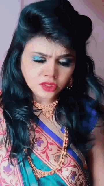 a woman with blue hair is wearing a necklace and a sari