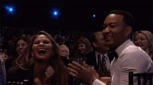 a man and a woman are laughing in a crowd while sitting in a theatre .