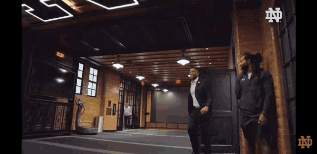 a man in a suit is walking in a room with a sign that says exit on it