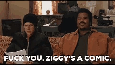 two men are sitting on a couch and one of them is holding a piece of paper and the other is holding a camera .