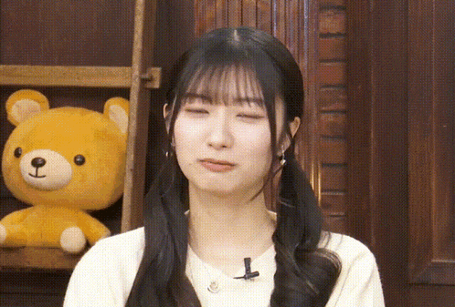 a girl with pigtails is standing in front of a teddy bear