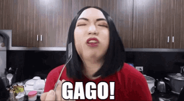 a woman in a red shirt is holding a fork in her mouth and making a face .