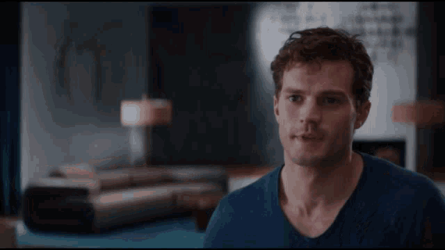 a man in a blue shirt looks at the camera in a living room