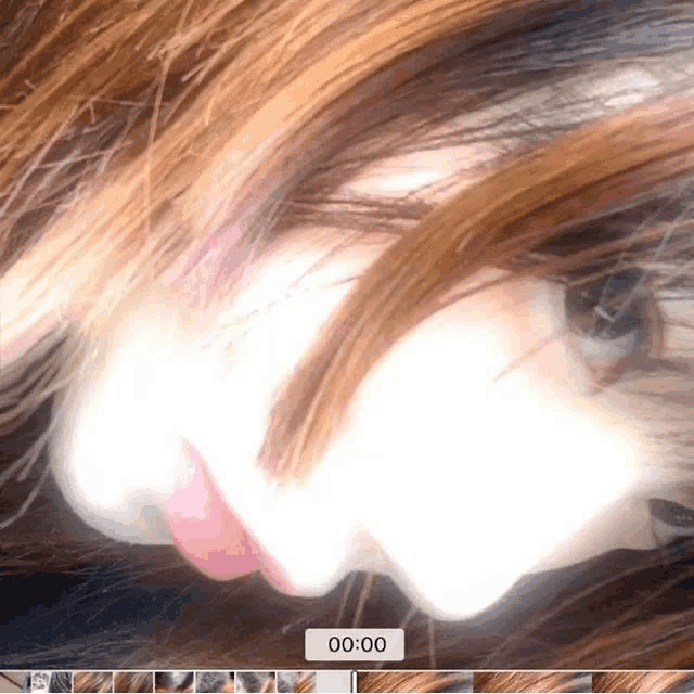 a close up of a woman 's face with a clock displaying 00:00