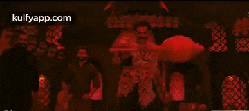 a man in a red costume is dancing in front of a crowd of people .