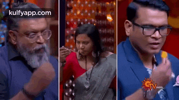 a man , a woman , and a man in a suit are eating food on a television show .