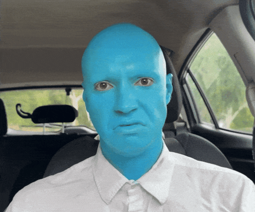 a man with blue paint on his face is sitting in the driver 's seat of a car