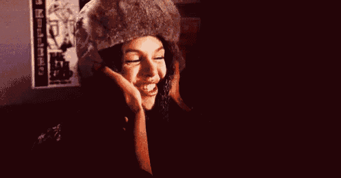 a woman wearing a fur hat is smiling while talking on a cell phone .