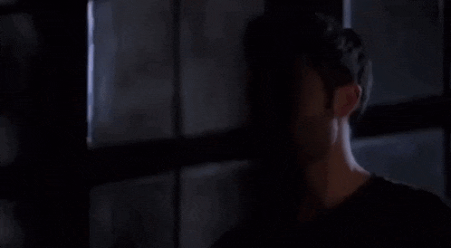 a man is standing in front of a window in a dark room