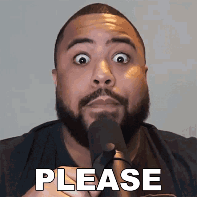 a man with a beard is talking into a microphone and the word please is on the front of his shirt