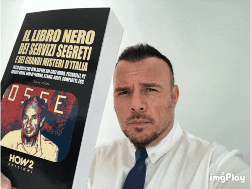 a man holds up a book titled il libro nero dei servizi segreti e dei grandi misteri d' italia