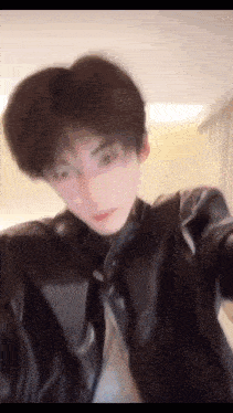 a blurry picture of a young man in a leather jacket and tie .